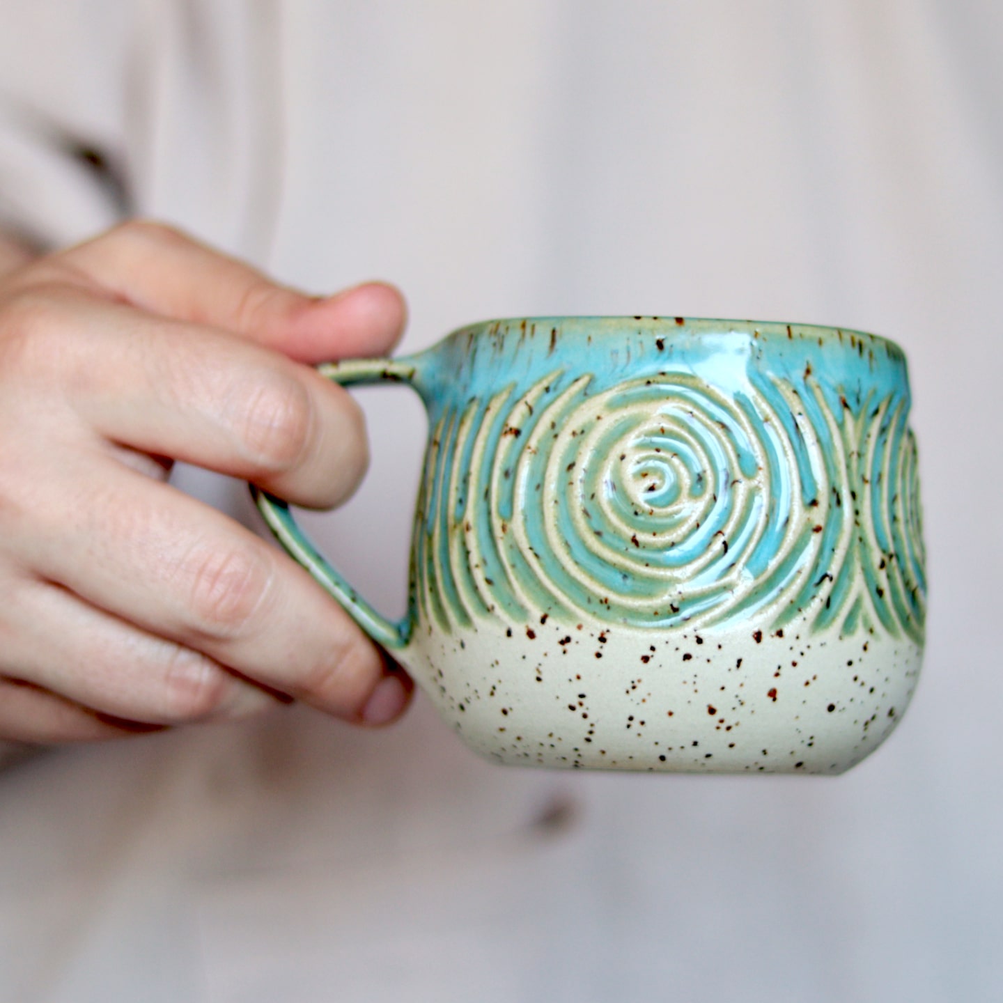 Hand-carved-pottery-mug-held Hand-carved-pottery-mug-held
