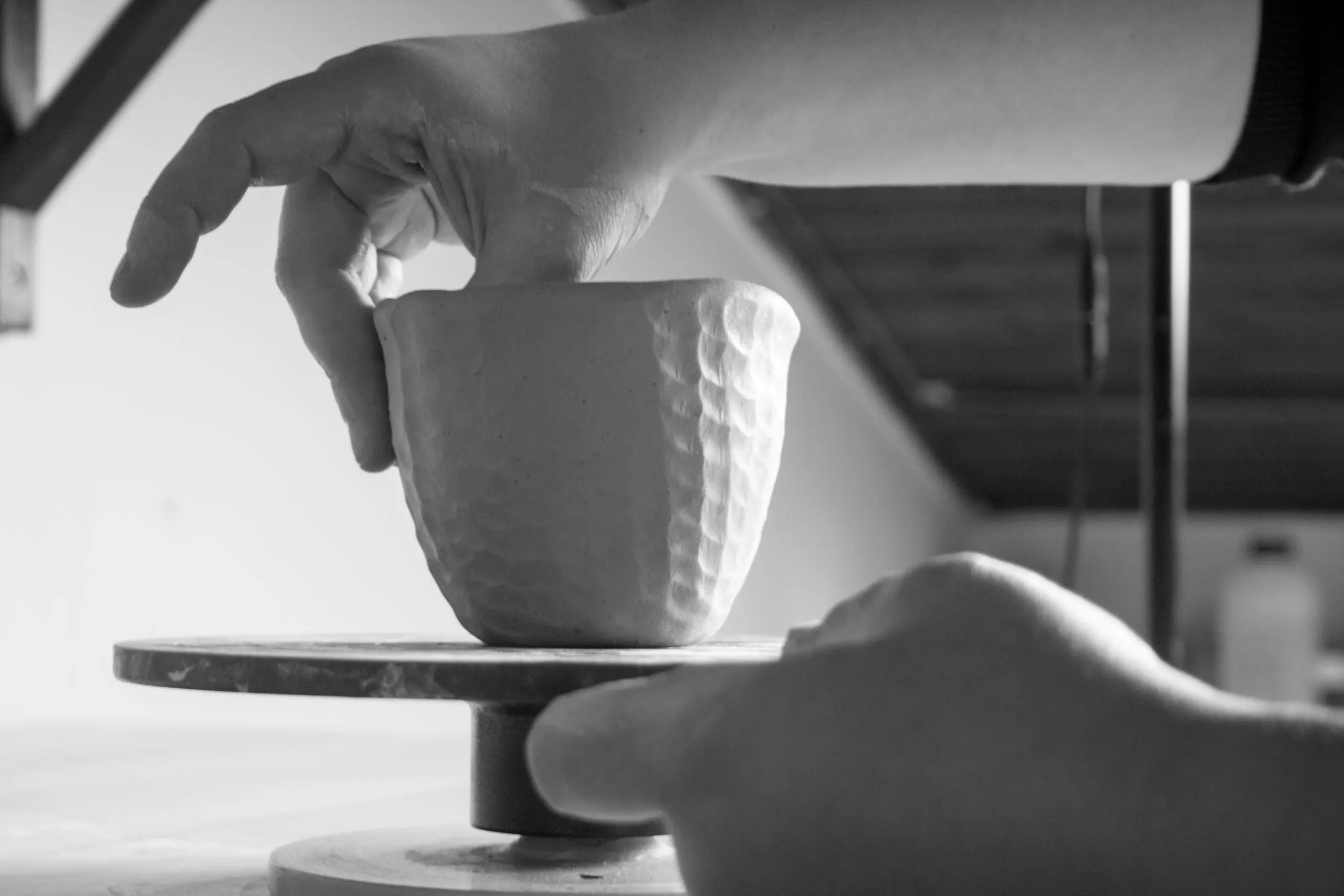 Close-up of hands shaping a stoneware cup using the traditional pinching technique by Seyma Ates.