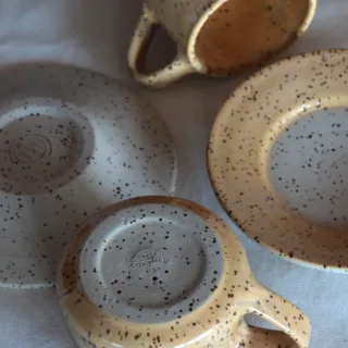 Bottom of handmade stoneware espresso cup and saucer showing potter's mark