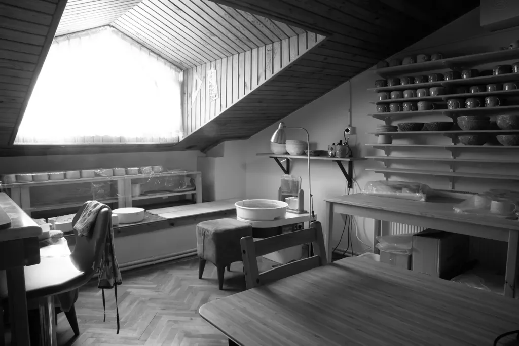 A black and white photograph of Seyma Ates's pottery workbench with tools and greenware drying on shelves.