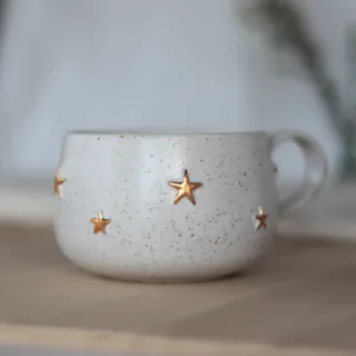 Handmade white speckled stoneware mug with raised gold stars, handmade pottery