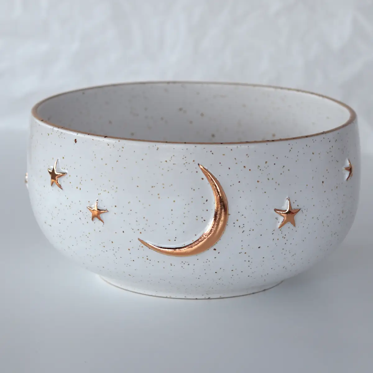 White ceramic celestial bowl with raised gold crescent moon and stars, handmade pottery